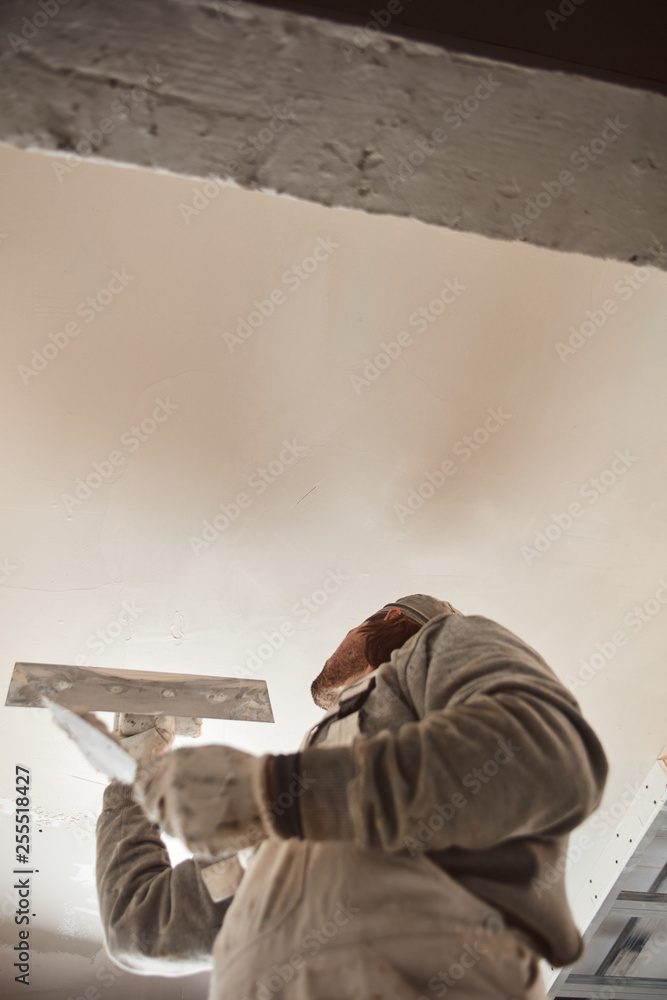 Worksman plastering gypsum walls inside the house.