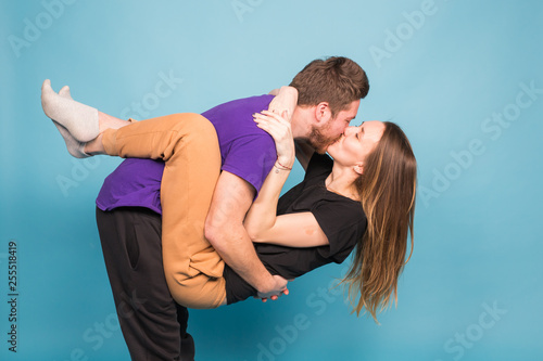 People, relationship and fun concept - Smiling man holding beautiful woman over blue background