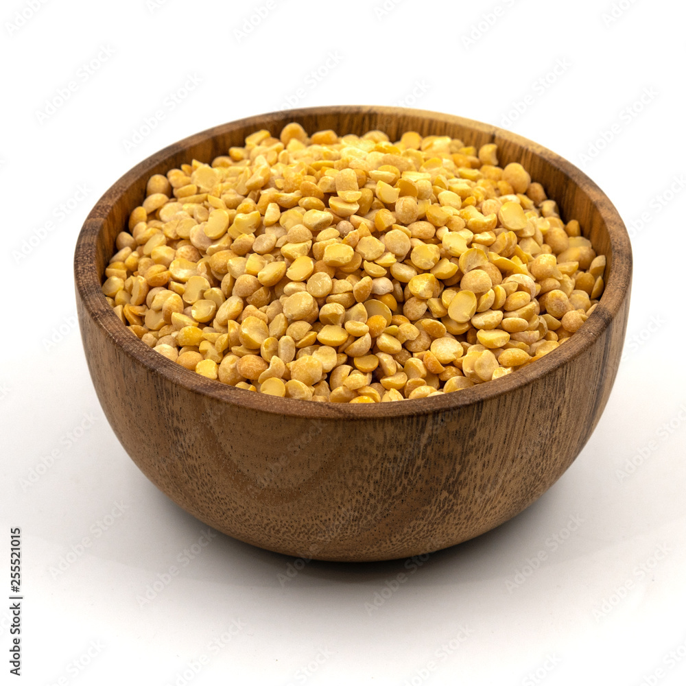 Raw yellow split peas in a wooden plate (bowl) isolated on white background