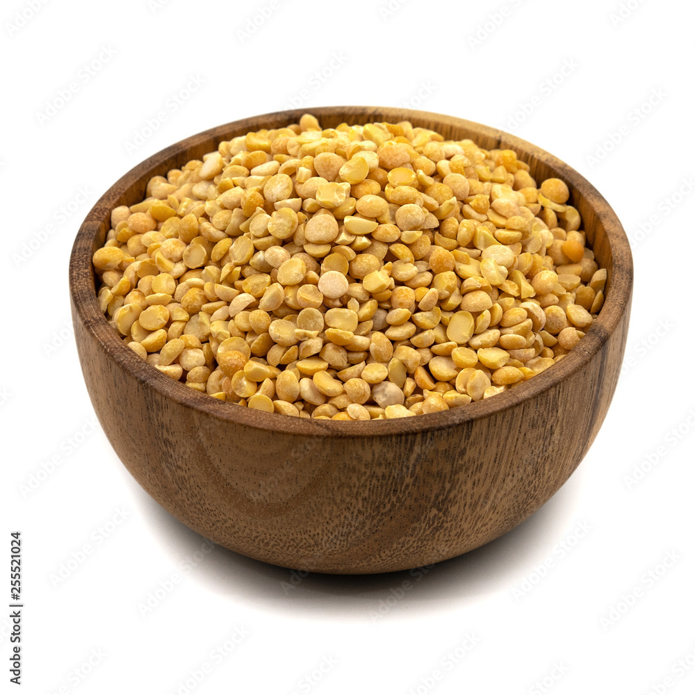 Raw yellow split peas in a wooden plate (bowl) isolated on white background