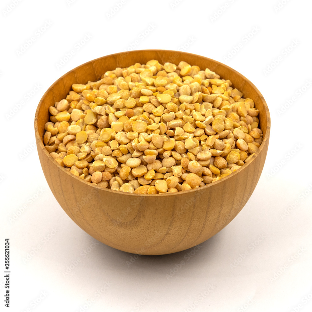 Raw yellow split peas in a wooden plate (bowl) isolated on white background Raw yellow split peas in a wooden plate (bowl) isolated on white background