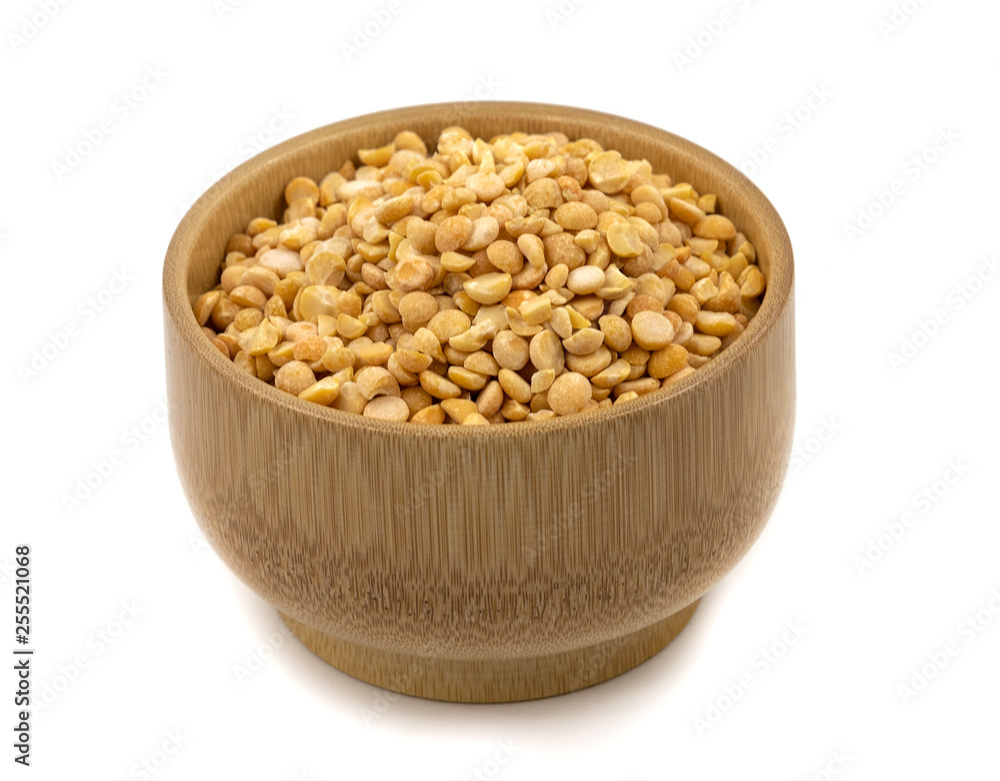Raw yellow split peas in a wooden plate (bowl) isolated on white background Raw yellow split peas in a wooden plate (bowl) isolated on white background