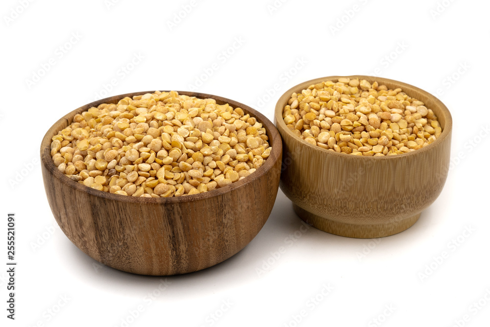 Raw yellow split peas in a wooden plate (bowl) isolated on white background Raw yellow split peas in a wooden plate (bowl) isolated on white background