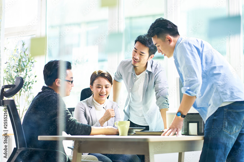 group of four asian teammates working together discussing business in office group of four asian teammates working together discussing business in office