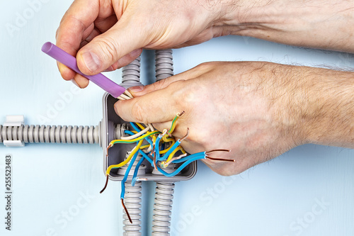 Worker twists wires with insulation shrinkable tube. photo