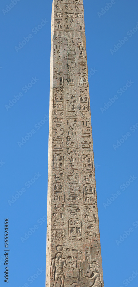 Egyptian obelisk with hieroglyphics and blue sky background