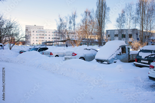 Snow-covered cars on the Parking lot, a snow storm in Russia. Snow removal utilities.