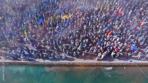 Aerial drone bird's eye view photo of people participating in traditional colourful flour war or Alevromoutzouromata part of Carnival festivities in historic port of Galaxidi, Fokida, Greece © aerial-drone