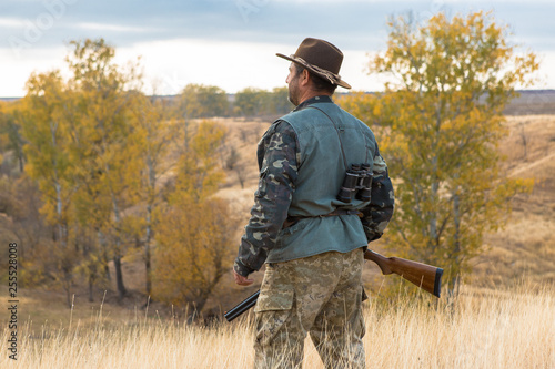 Hunter with a hat and a gun in search of prey in the steppe 