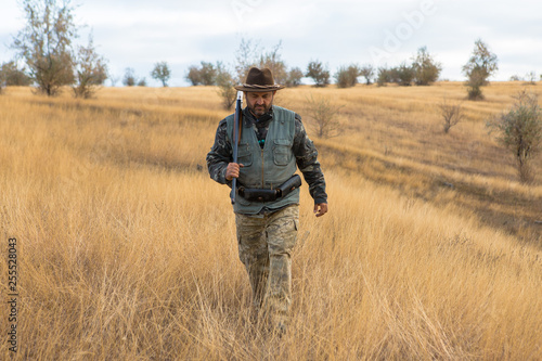 Hunter with a hat and a gun in search of prey in the steppe  © Mountains Hunter
