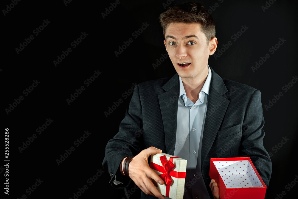 A man in a suit holds a gift box in his hands. Box with a red ribbon and a bow. A man in a suit holds a gift box in his hands. Box with a red ribbon and a bow.
