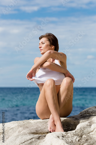 Female person resting on wild rocky seashore