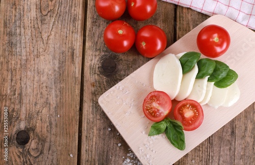 fresh tomatoes with mozzarella cheese and basil on a rustic wooden table - healthy breakfast - top view