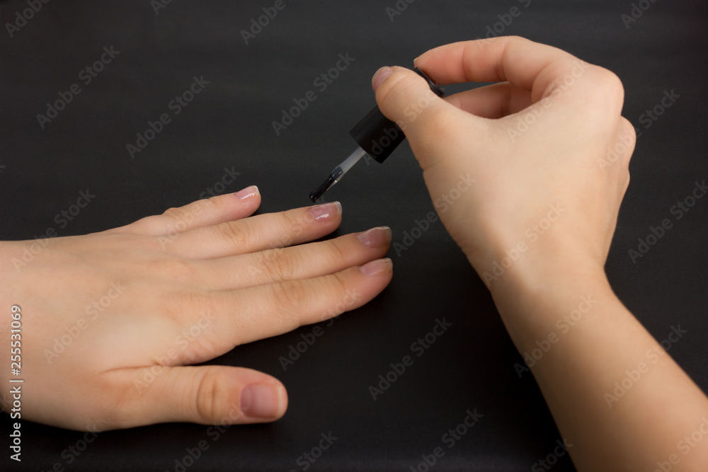 The hands of a young girl make a manicure with shellac coating and nail strengthening The hands of a young girl make a manicure with shellac coating and nail strengthening