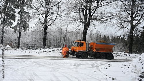 View of snowplow service truck - gritter car spreading salt on the road. Maintenance of roads in winter in the mountains.
