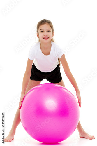 little girl doing exercises on a big ball for fitness.