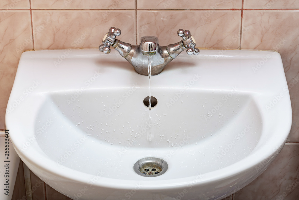Horizontal image of a tap with water flowing slowly during a period of scarcity Horizontal image of a tap with water flowing slowly during a period of scarcity