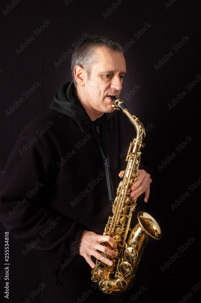Fototapeta premium Muzyk grający muzykę jazzową na swoim saksofonie, na czarnym tle