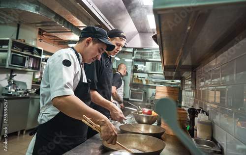New skills. Two chef assistants cooking a new dish in a restaurant kitchen. photo