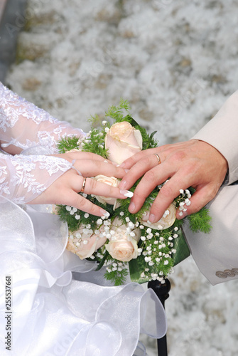 Hands and rings on wedding bouquet and groom hand
