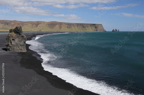 Reynisfjara black basalt sand beach with large rock near Vik, Iceland