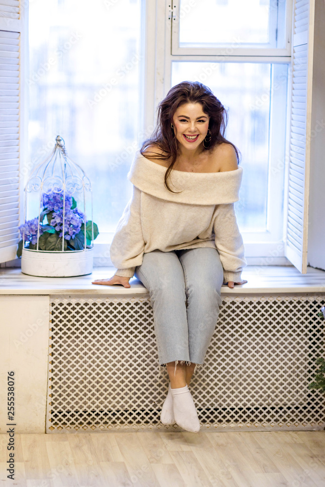 Beautiful brunette woman in a white sweater in a cozy room dreams of life Beautiful brunette woman in a white sweater in a cozy room dreams of life