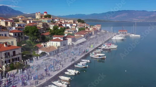 Aerial drone bird's eye view video of people participating in traditional colourful flour war or Alevromoutzouromata part of Carnival festivities in historic port of Galaxidi, Fokida, Greece photo