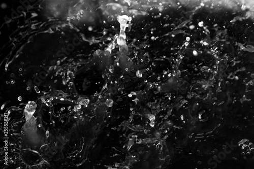 Water splash in dark with a drops of water flying, defocused bokeh 
