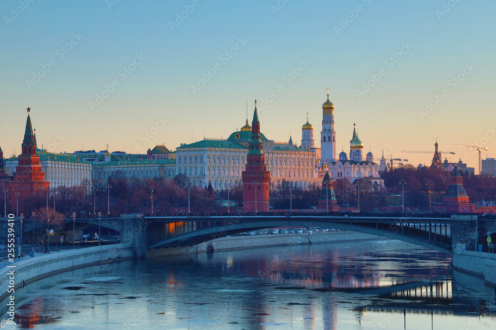 Moscow Kremlin and Bolshoy Kamenny Bridge in Russia in the rays of rising sun. View from the Patriarshy pedestrian Bridge. Morning urban landscape in the gold hour