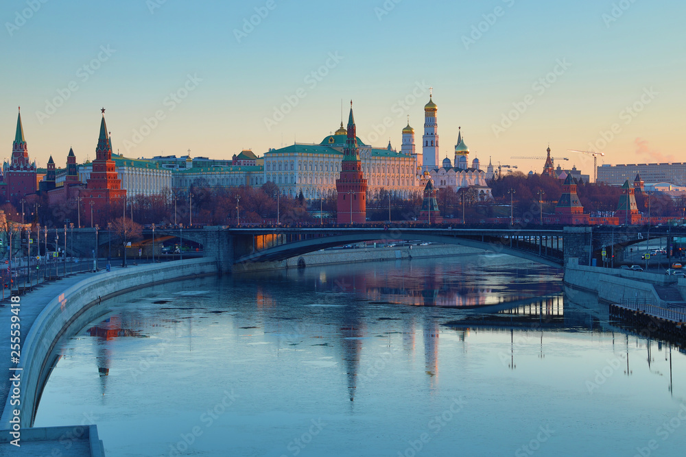 Fototapeta premium Moscow Kremlin and Bolshoy Kamenny Bridge in Russia in the rays of rising sun. View from the Patriarshy pedestrian Bridge. Morning urban landscape in the gold hour