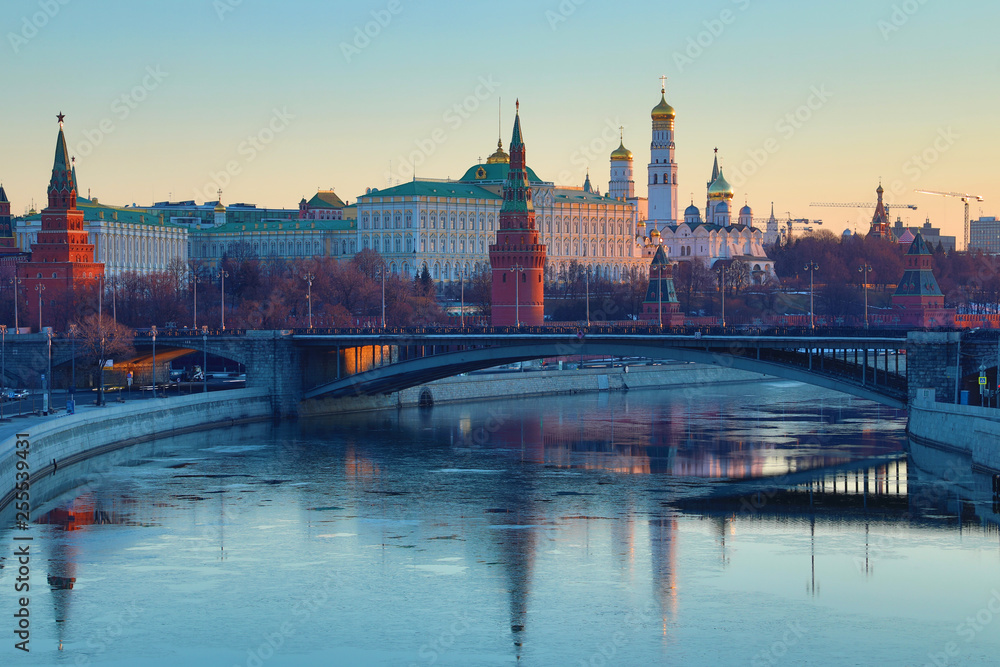 Obraz premium Moscow Kremlin and Bolshoy Kamenny Bridge in Russia in the rays of rising sun. View from the Patriarshy pedestrian Bridge. Morning urban landscape in the gold hour