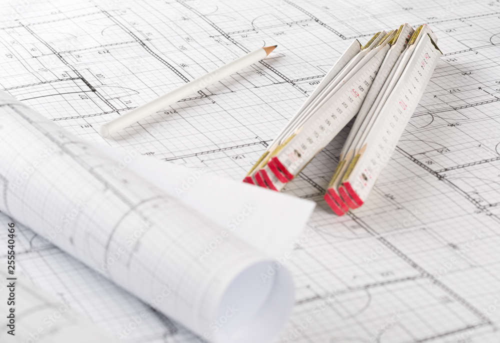 Rolls of architectural blueprint house building plans with pencil and folding ruler on blueprint background Rolls of architectural blueprint house building plans with pencil and folding ruler on blueprint background