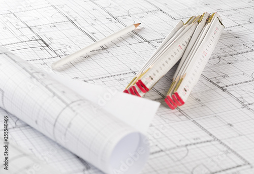 Rolls of architectural blueprint house building plans with pencil and folding ruler on blueprint background