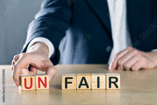 Business man puts away first two letters from the word unfair, so it becomes fair; sports or business fair play concept photo