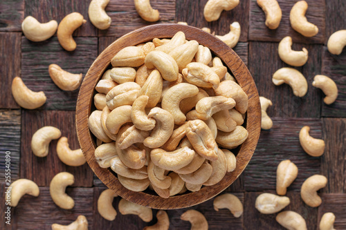 Photos cashew nuts peeled roasted in wooden bowl, top view.