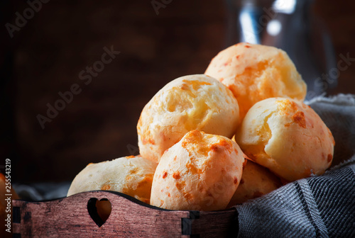 Delicious homemade golden cheese savory buns in tray, vintage wooden rustic table background, selective focus photo