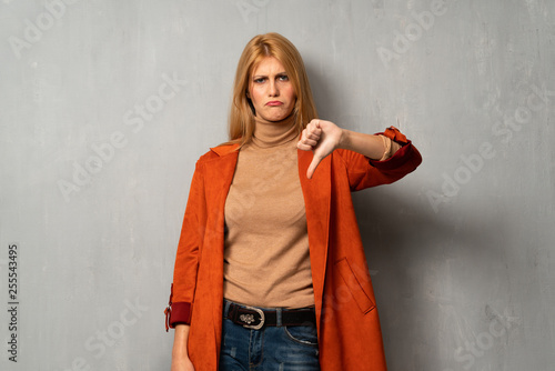 Woman over textured background showing thumb down with both hands © luismolinero