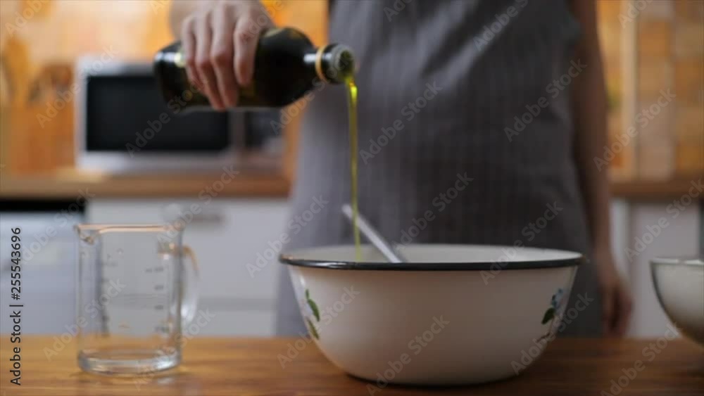 Woman hands add olive oil into bowl with flour, slow motion Woman hands add olive oil into bowl with flour, slow motion