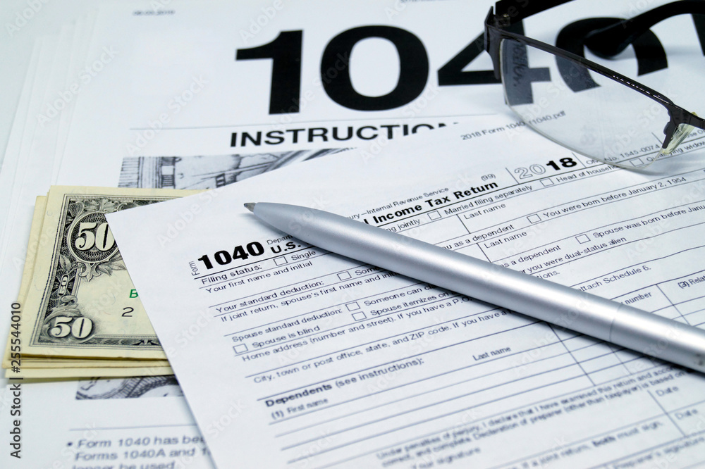 Income tax form with instruction, glasses and pen.