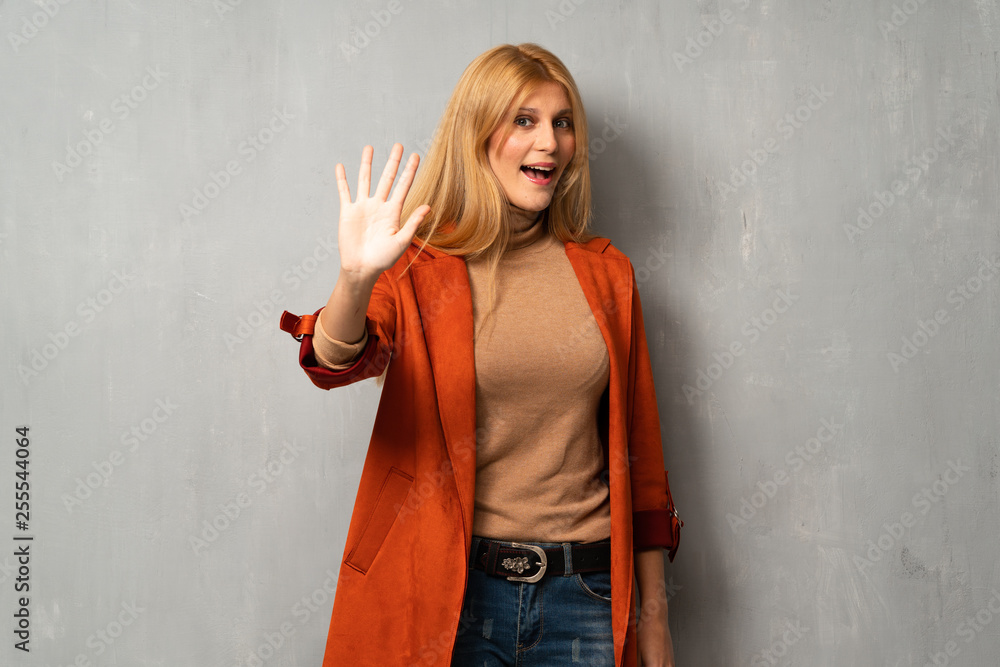 Woman over textured background saluting with hand with happy expression Woman over textured background saluting with hand with happy expression