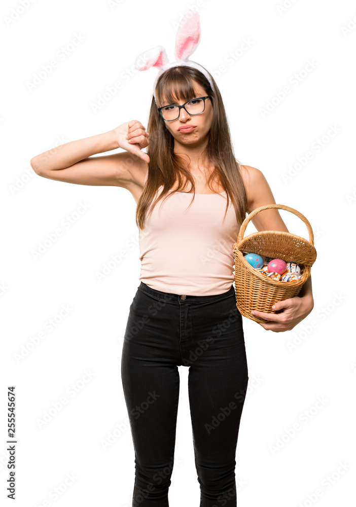 Young woman wearing bunny ears for Easter holidays showing thumb down sign with negative expression on isolated white background Young woman wearing bunny ears for Easter holidays showing thumb down sign with negative expression on isolated white background