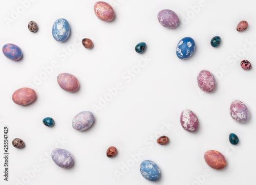 Creative Frame background with quail, pink, purple and blue easter eggs with copy space for text. isolated on white background. Flat lay, top view.