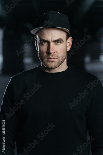 Portrait of man. He is wearing a black sweatshirt and cap. Copy space for your advertising