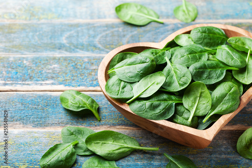 Baby spinach leaves in bowl on wooden table. Organic and healthy food. photo