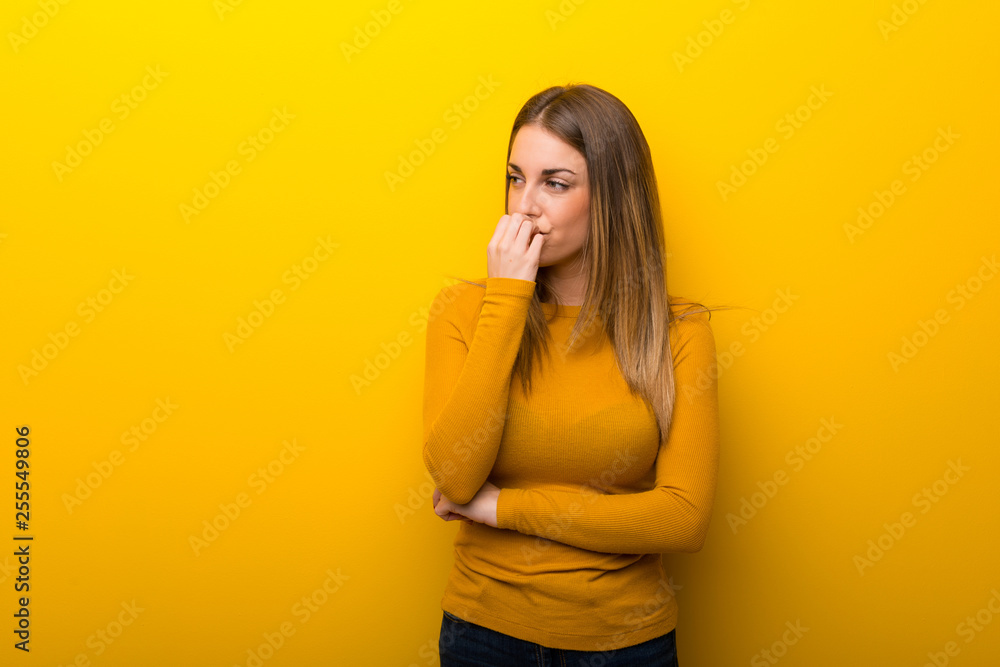 Young woman on yellow background having doubts