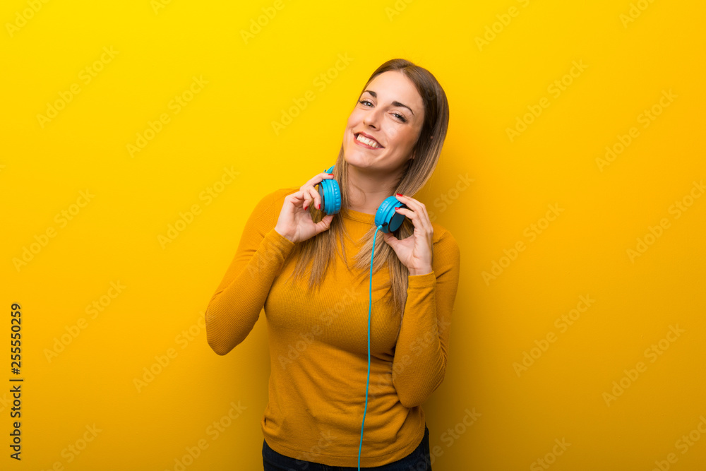 Young woman on yellow background with headphones Young woman on yellow background with headphones