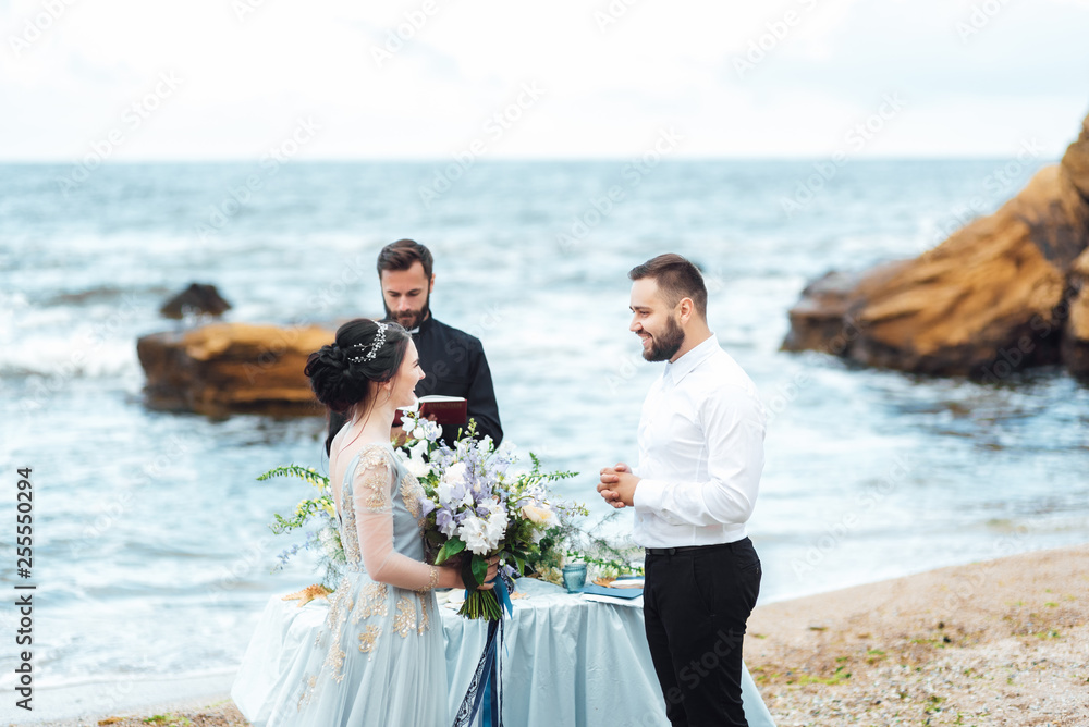 wedding couple on the ocean with a priest wedding couple on the ocean with a priest