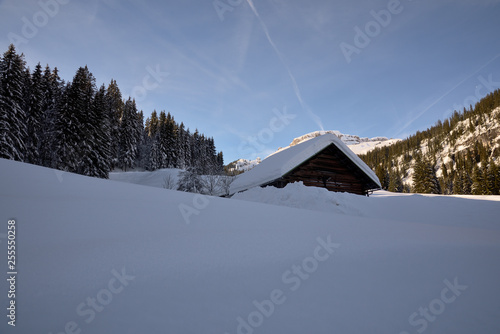 Alpine Winterlandschaft und eine eingeschneite Holzhütte © Fotolla