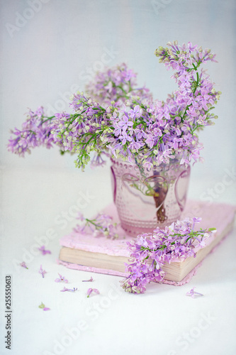 A beautiful purple lilac in a vase on a table.Blue background.Pastel tonality