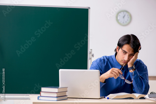 Young male teacher in front of chalkboard 